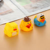 Three yellow and blue rubber duck bath toys are displayed on a light surface.