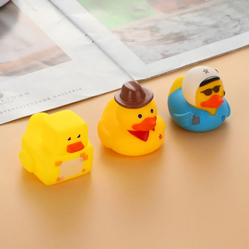 Three yellow and blue rubber duck bath toys are displayed on a light surface.