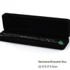 A black velvet box containing a silver necklace with a green pendant.