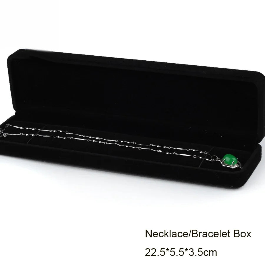 A black velvet box containing a silver necklace with a green pendant.