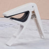 A white adjustable guitar capo with a black bridge pin puller mechanism shown on a white surface.