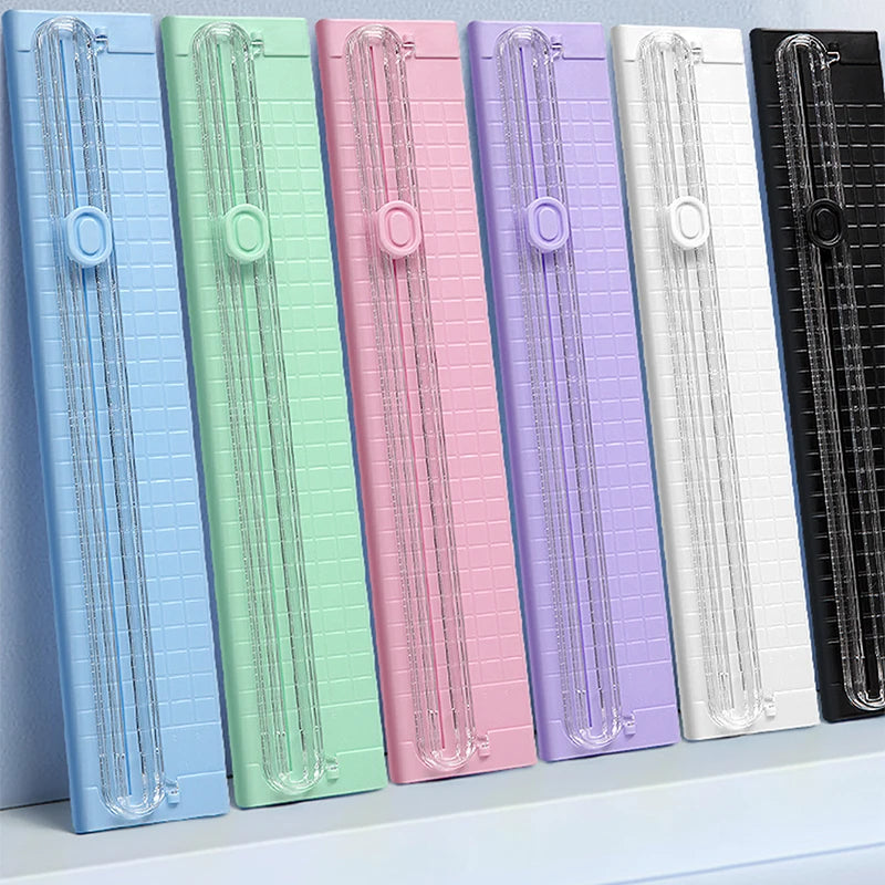 A row of colorful portable paper cutters or trimmers, featuring various shades of blue, green, pink, and purple.