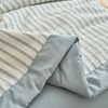 A close-up of a light blue and white striped breathable summer quilt with a jacquard cotton cover.