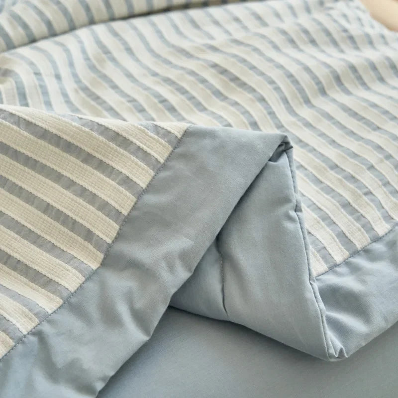 A close-up of a light blue and white striped breathable summer quilt with a jacquard cotton cover.