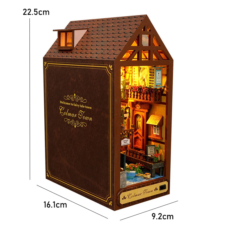 A miniature DIY book nook kit featuring a brown wooden house with a tiled roof and an illuminated interior scene.