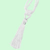 A white braided cord with a tassel used as an elegant curtain tieback.