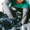 A person wearing gray cut-resistant arm sleeves is working on machinery, using gloves and tools.