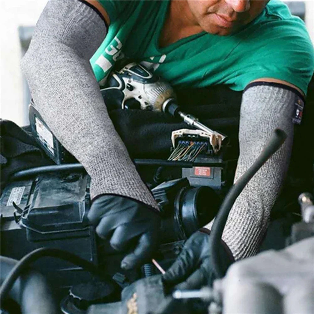 A person wearing gray cut-resistant arm sleeves is working on machinery, using gloves and tools.