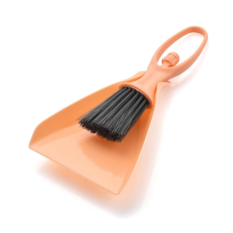 An orange compact mini broom and dustpan set with a handle and bristles for cleaning desks and keyboards.