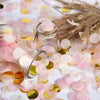 Rosa und goldener Papierschnipsel-Confetti auf weißer Fläche neben einem Glasgefäß