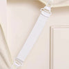 White adjustable bed sheet holder clips attached to a light-colored wooden surface.