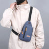 A person wearing a beige jacket is holding an Oxford canvas crossbody chest bag with multiple pockets.