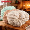 A pile of light beige and pink chunky chenille yarn for knitting and crochet displayed on a wooden surface.