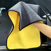 A yellow microfiber cleaning towel is shown next to a gray towel inside a car window.