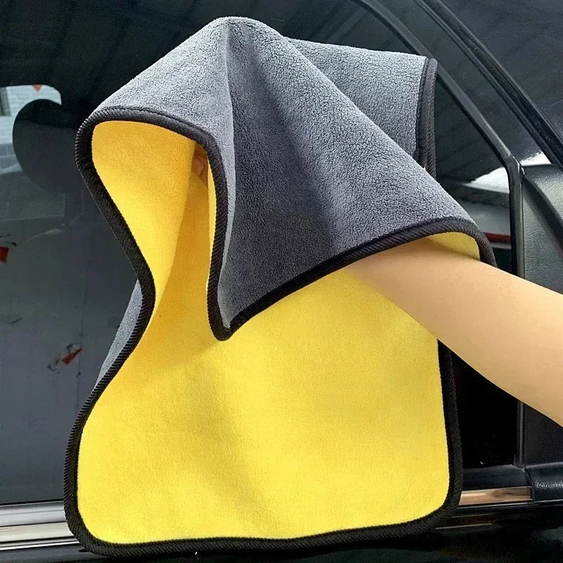 A yellow microfiber cleaning towel is shown next to a gray towel inside a car window.