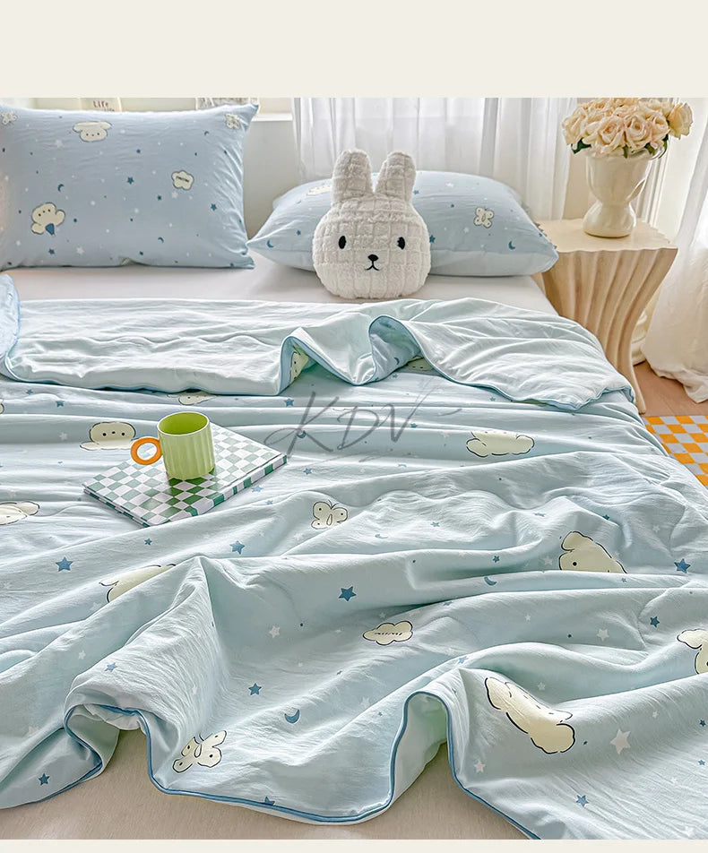 Light blue quilt with a pastoral print featuring clouds, stars, and a cream-colored stuffed animal.