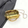 A small, rectangular gold metal clutch bag with a gold chain strap is shown against a gray fabric background.