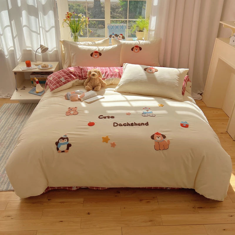 A beige duvet cover set featuring embroidered cartoon animals like bears and penguins on a bed.