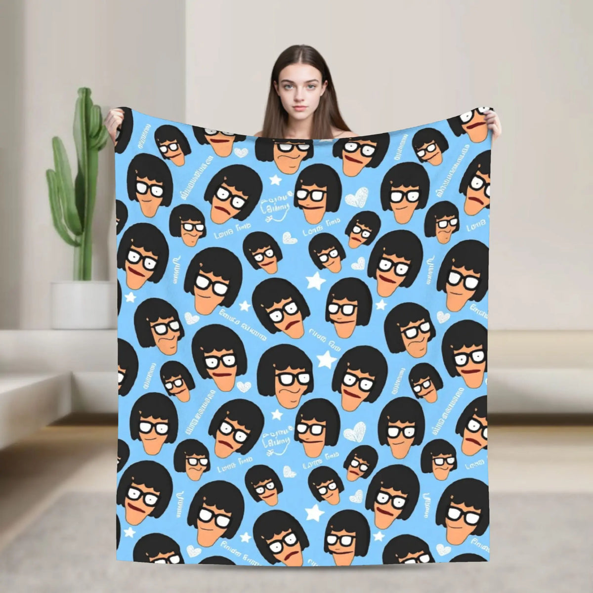 A blue cartoon throw blanket featuring multiple stylized characters with black hair and orange noses.