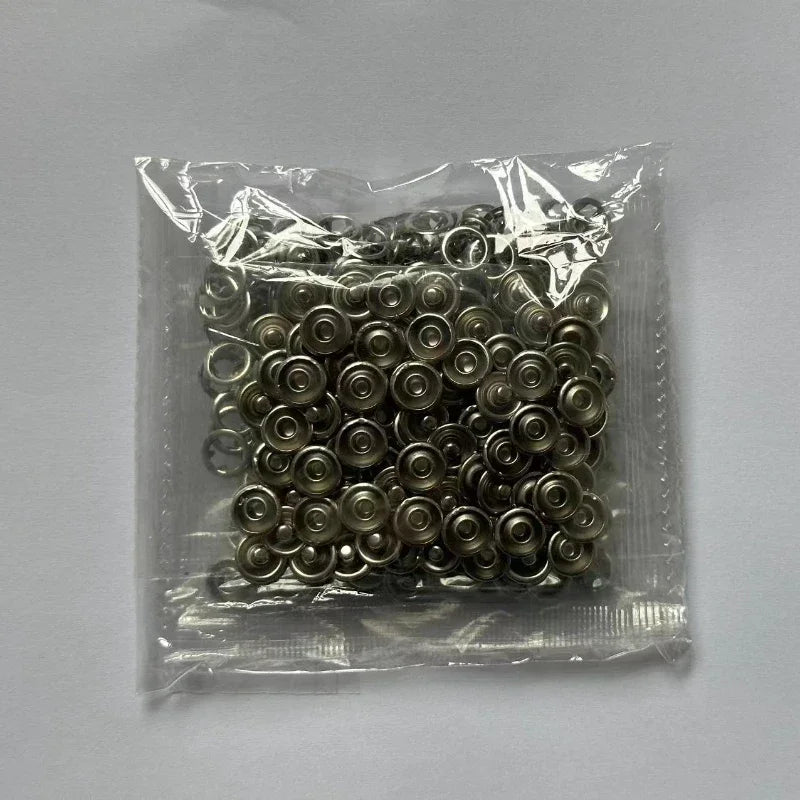 Bolsa de plástico transparente con un juego de pequeñas abrazaderas de hebilla metálicas redondas.