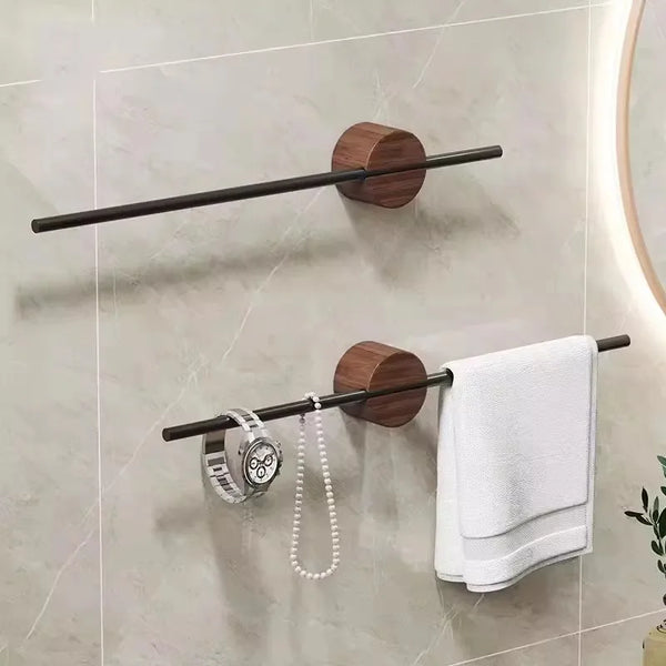 Un rack de toallas de madera con barra y soporte redondo, colgado en la pared, sosteniendo una toalla blanca.