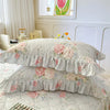 A set of two floral cotton pillowcases with ruffled edges displayed on a bed.