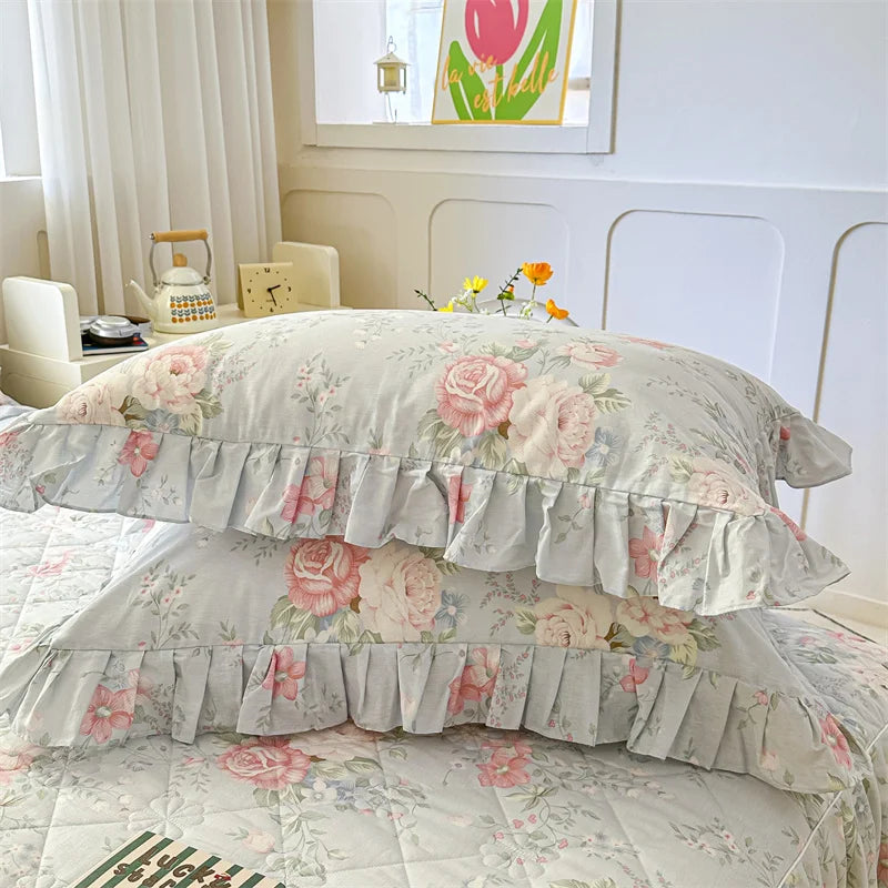 A set of two floral cotton pillowcases with ruffled edges displayed on a bed.