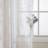 White vintage floral lace curtain panel filtering light through a window.