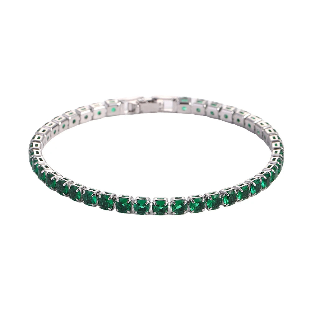 A tennis bracelet featuring green gemstones set in a silver-toned band.
