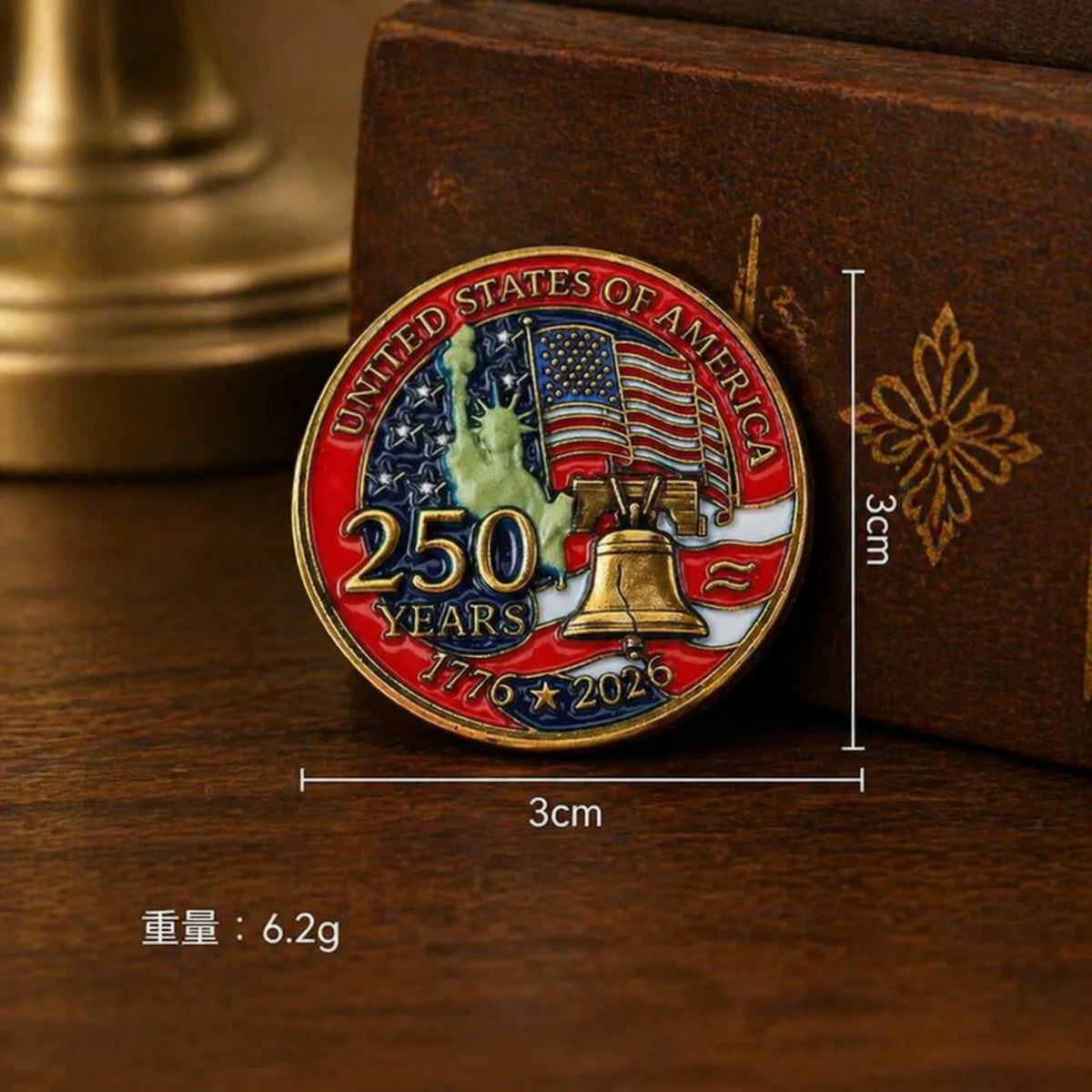 A round enamel pin featuring the United States of America design with an eagle and a bell, set against a brown box.
