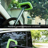 A green windshield cleaning brush is shown being used to wipe a car window.