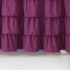 A deep purple ruffled bed skirt made of elastic fabric covering the bottom of a mattress.