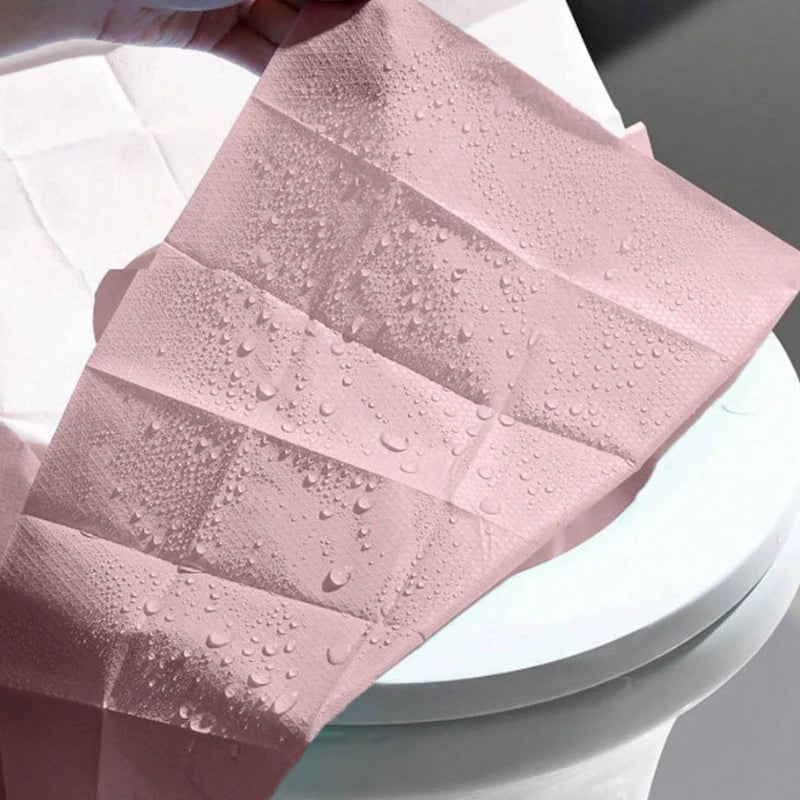 Pink disposable toilet seat covers with water droplets on a white toilet bowl