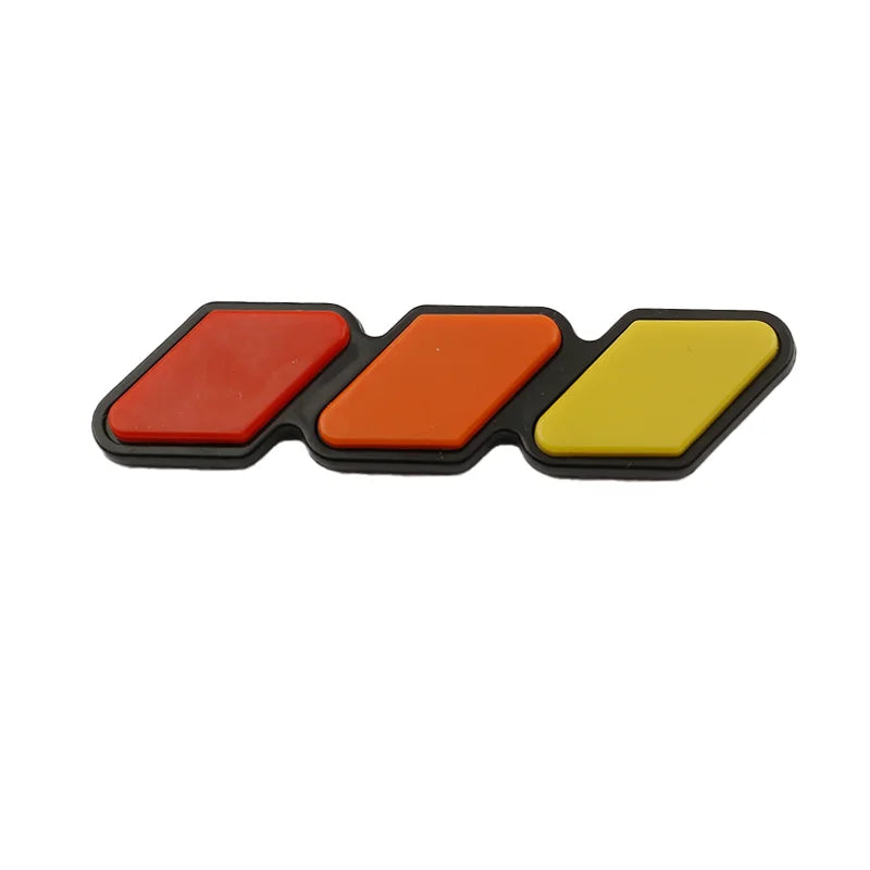 A set of three colored, rectangular grille emblem stickers in red, orange, and yellow.