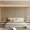 A modern bedroom featuring a bed with white linens against a wall of vertical wood slat panels.