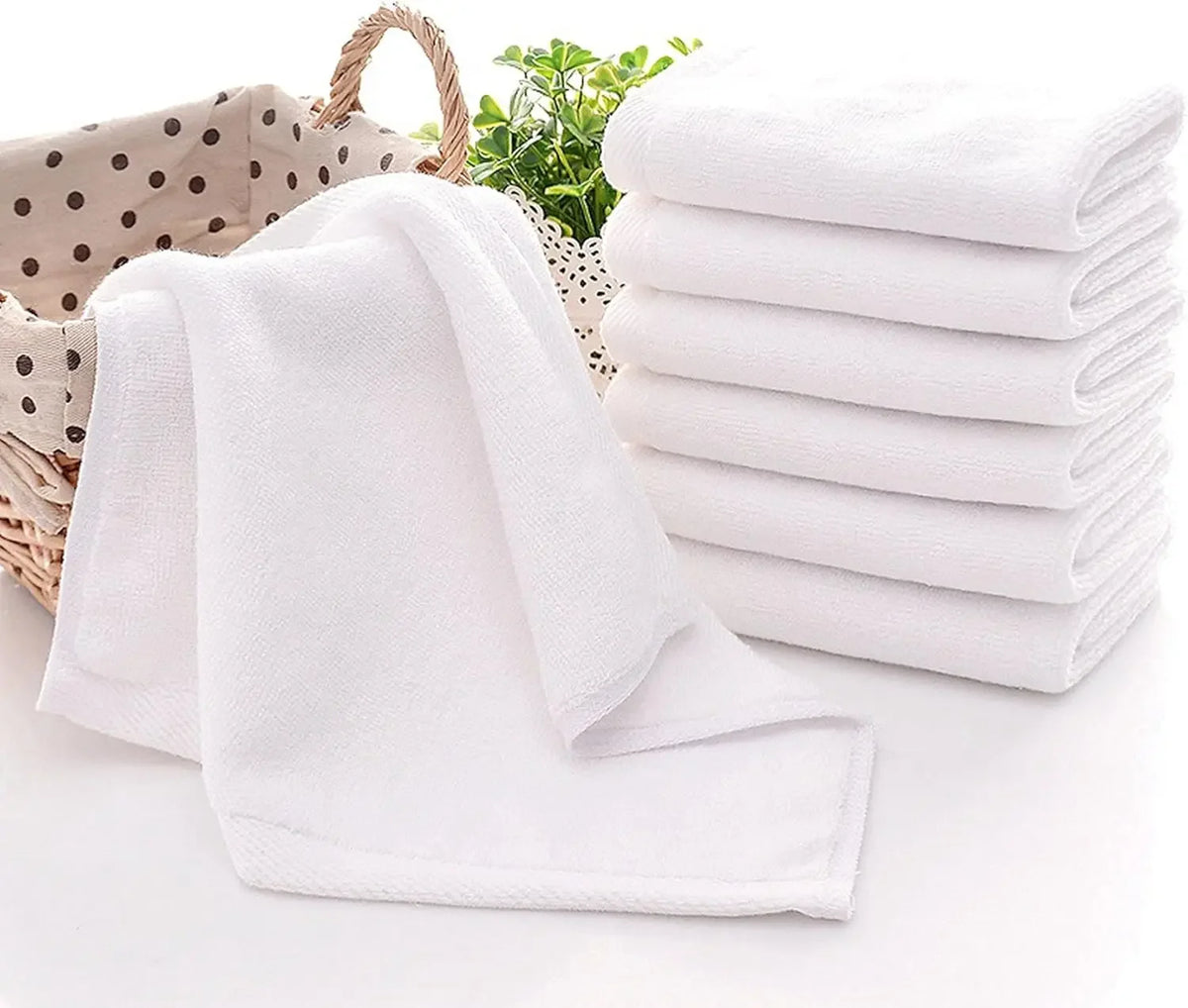 A stack of white soft cotton terry cloth face towels is shown next to a folded towel on a white surface.