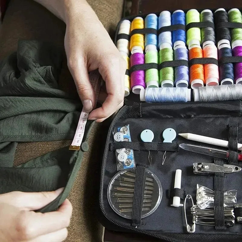 A hand is shown holding a compact portable sewing kit with various threads and tools inside a black pouch.