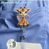 A 2D acrylic flat giraffe charm is clipped onto a blue fabric, demonstrating the product's size.