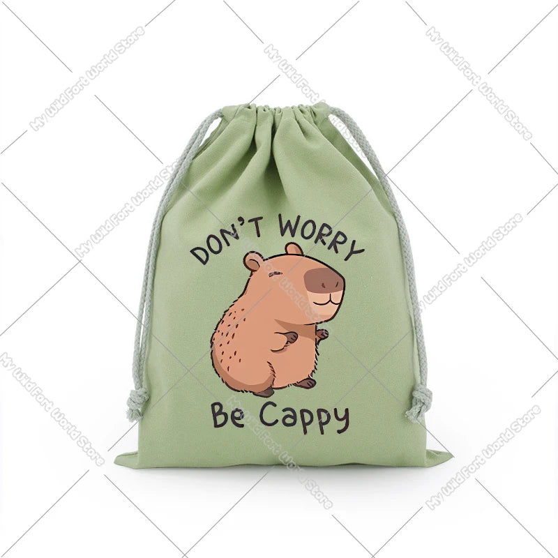 A light green drawstring storage bag featuring text that reads Don't Worry Be Cappy and an illustration of a capybara.