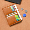 A brown leather compact wallet holding various credit cards and coins on a tan background.