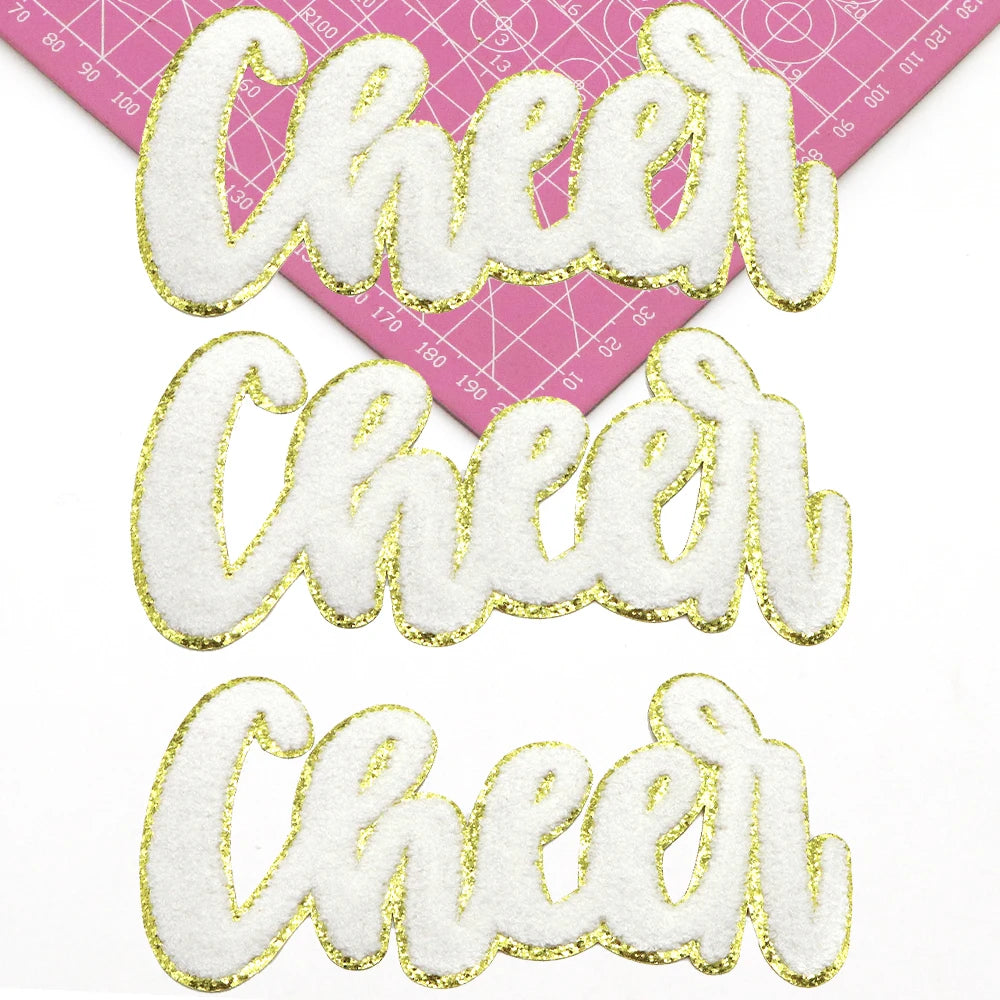 Three gold glitter chenille letter patches spelling Cheer in various script styles