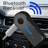 A black Bluetooth receiver with a microphone adapter is shown resting on a car dashboard.
