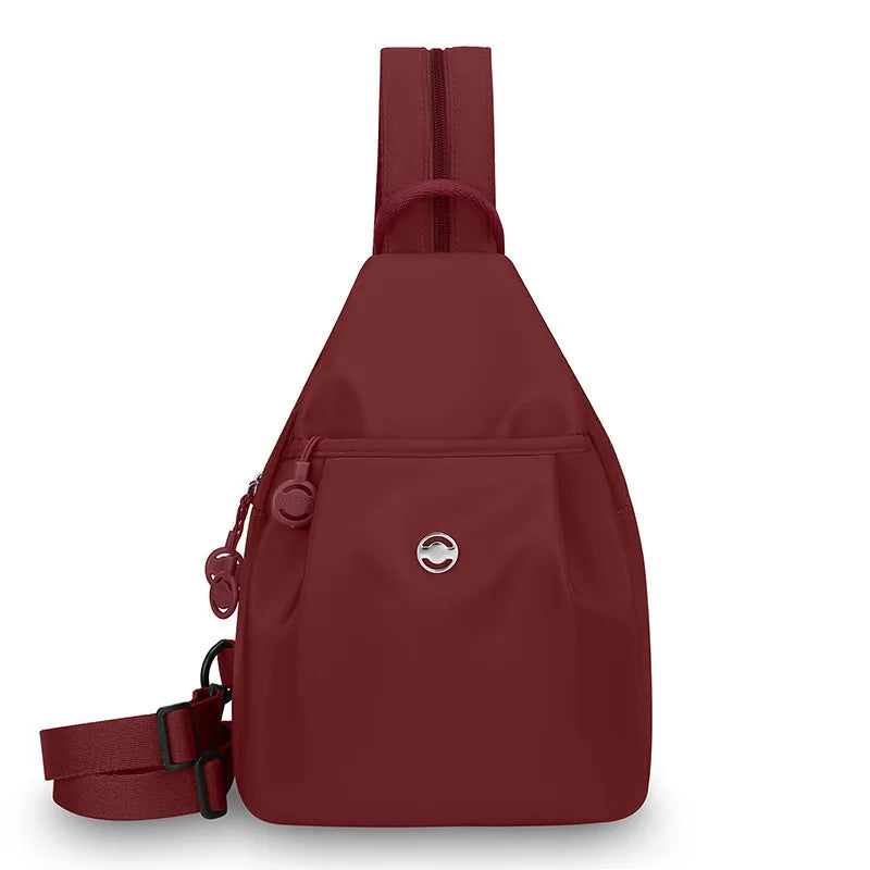 A maroon women's lightweight mini backpack with a chest strap visible from the front.