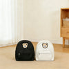A black and white embroidered bear stroller organizer bag resting on a light wooden floor.