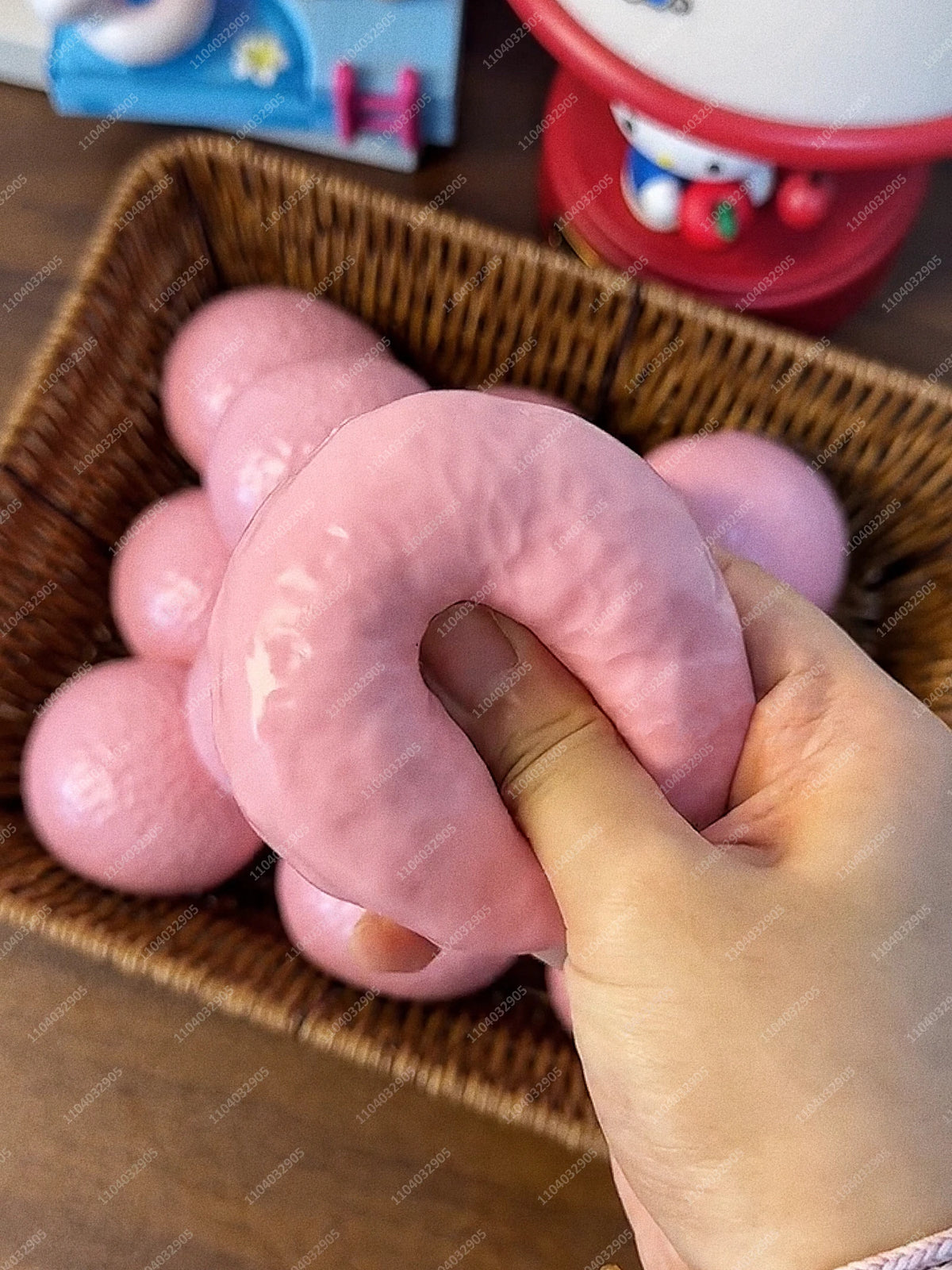 Eine Hand hält einen rosa, quetschbaren Kartoffel-Stressball-Spielzeug in einem geflochtenen Korb.