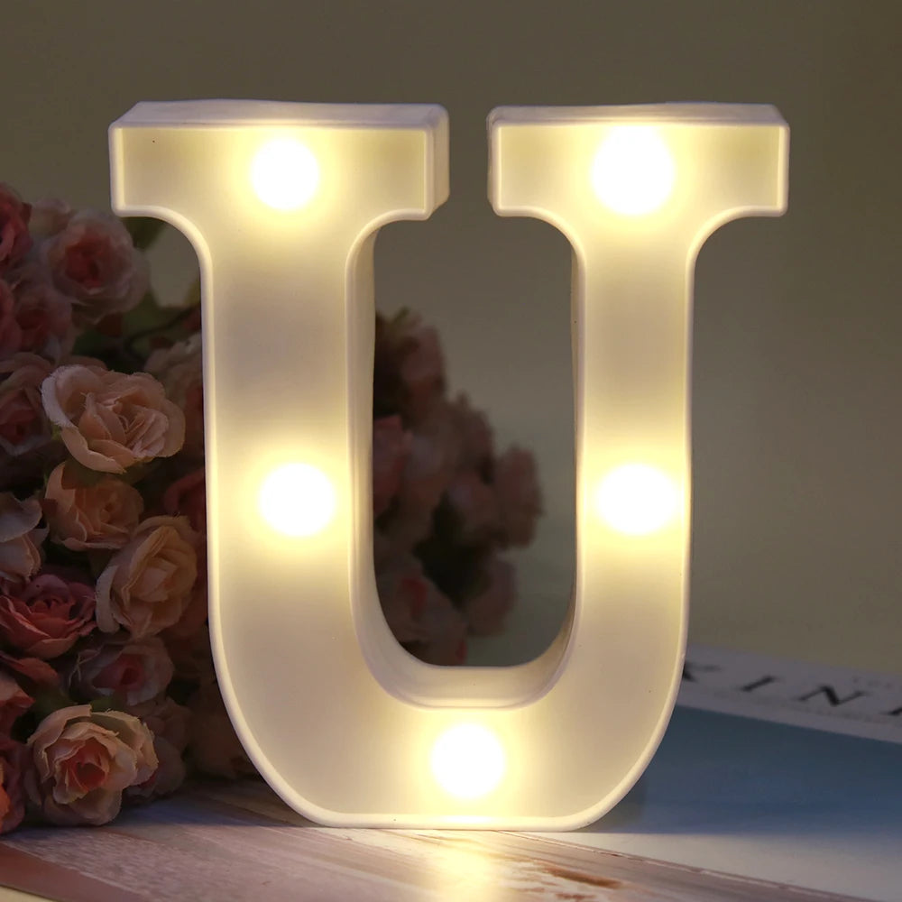 Lumière de nuit alphabet en LED blanche en forme de lettre U, éclairée sur une surface en bois.