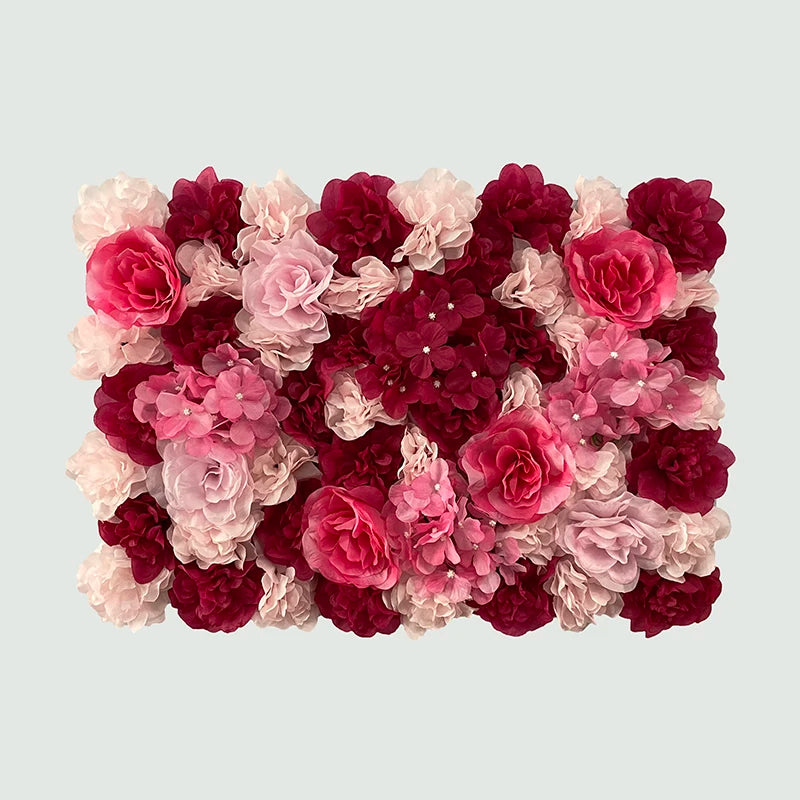 A dense wall panel of pink and deep red silk rose flowers for weddings and events.