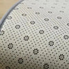 Close-up view of a white plush silk-touch area rug with small black floral and dot patterns.