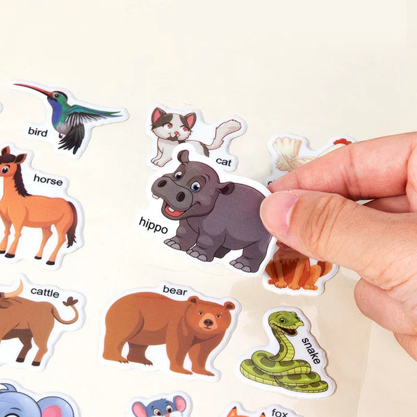 Une main tient une feuille d'autocollants en carton réutilisables avec des animaux comme un oiseau, un cheval, un chat, un hi