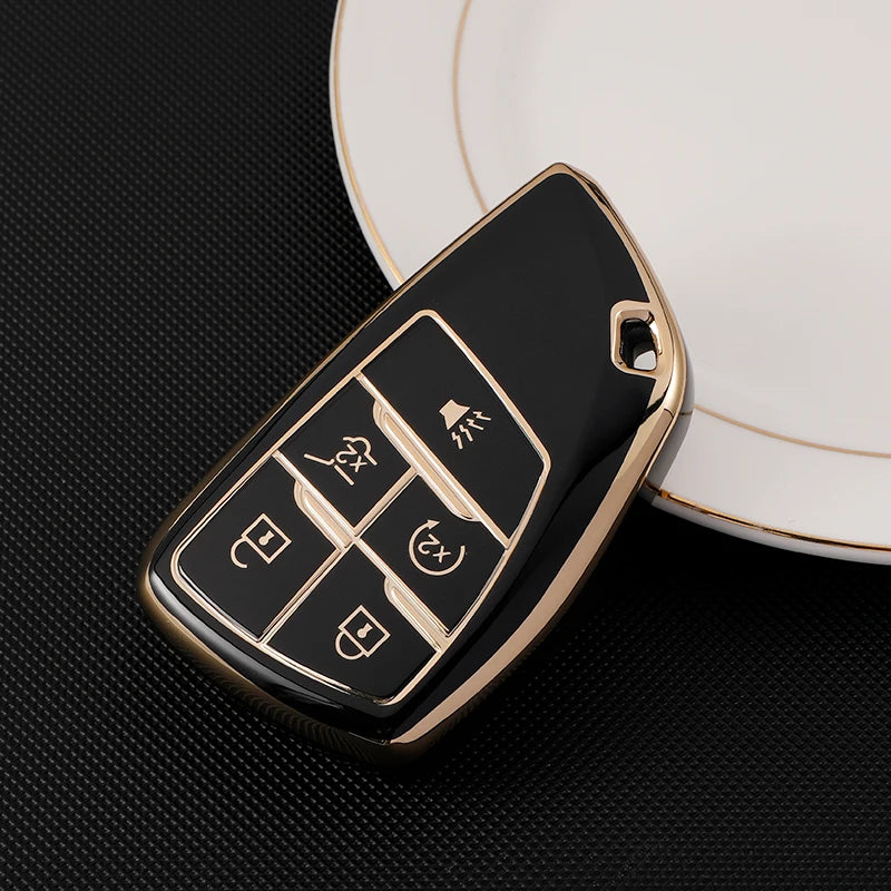 A black durable TPU car key fob cover with gold accents resting on a white plate.